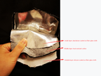 Hand holding a layered material with labeled layers on a black background