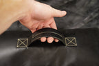 Hand holding a black leather belt with gold stitching on a dark background
